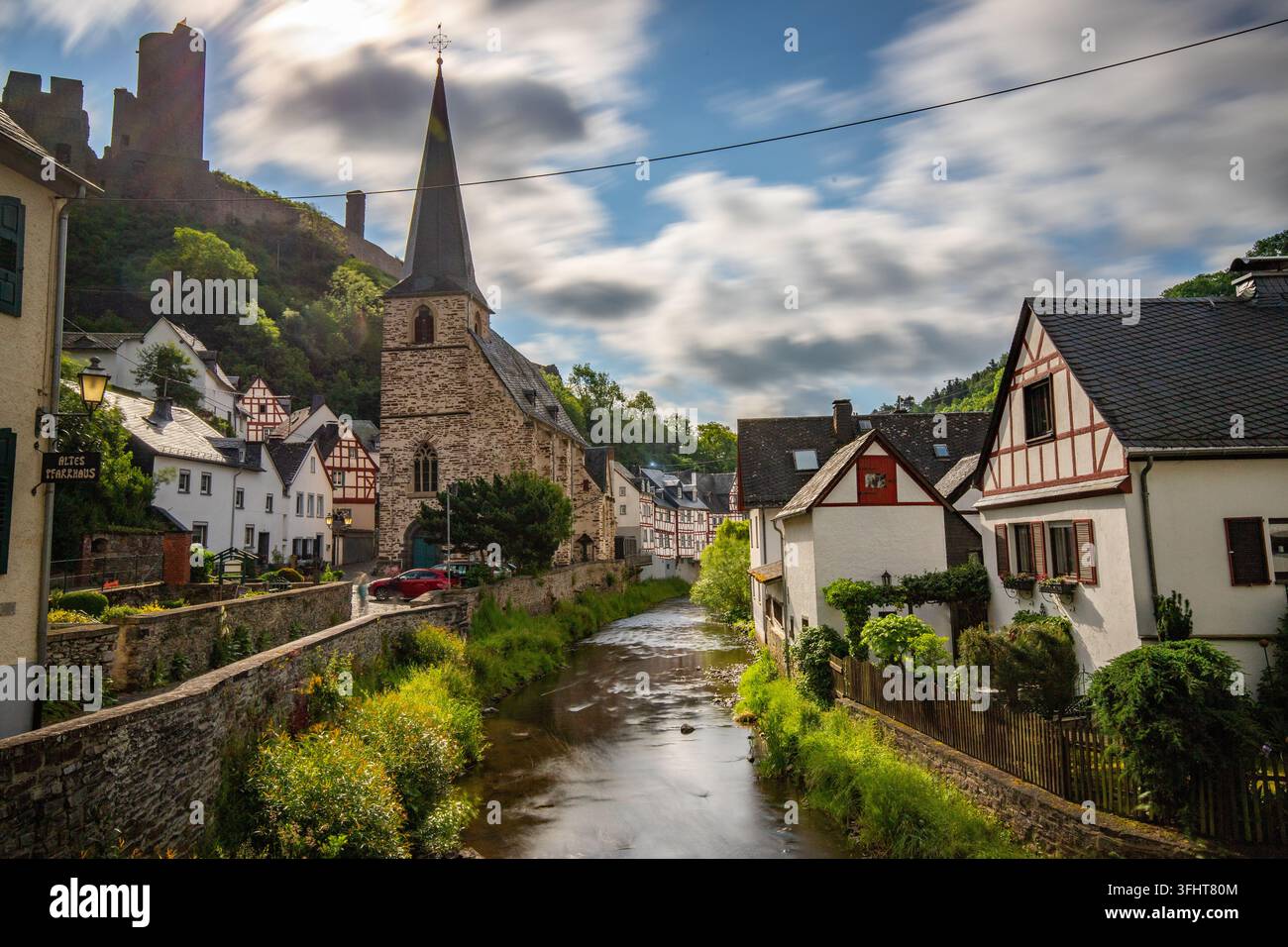 Paesaggio di un villaggio in legno lungo un fiume, circondato da colline e un castello. Città di Monreal sull'Elzbach, Germania Foto Stock