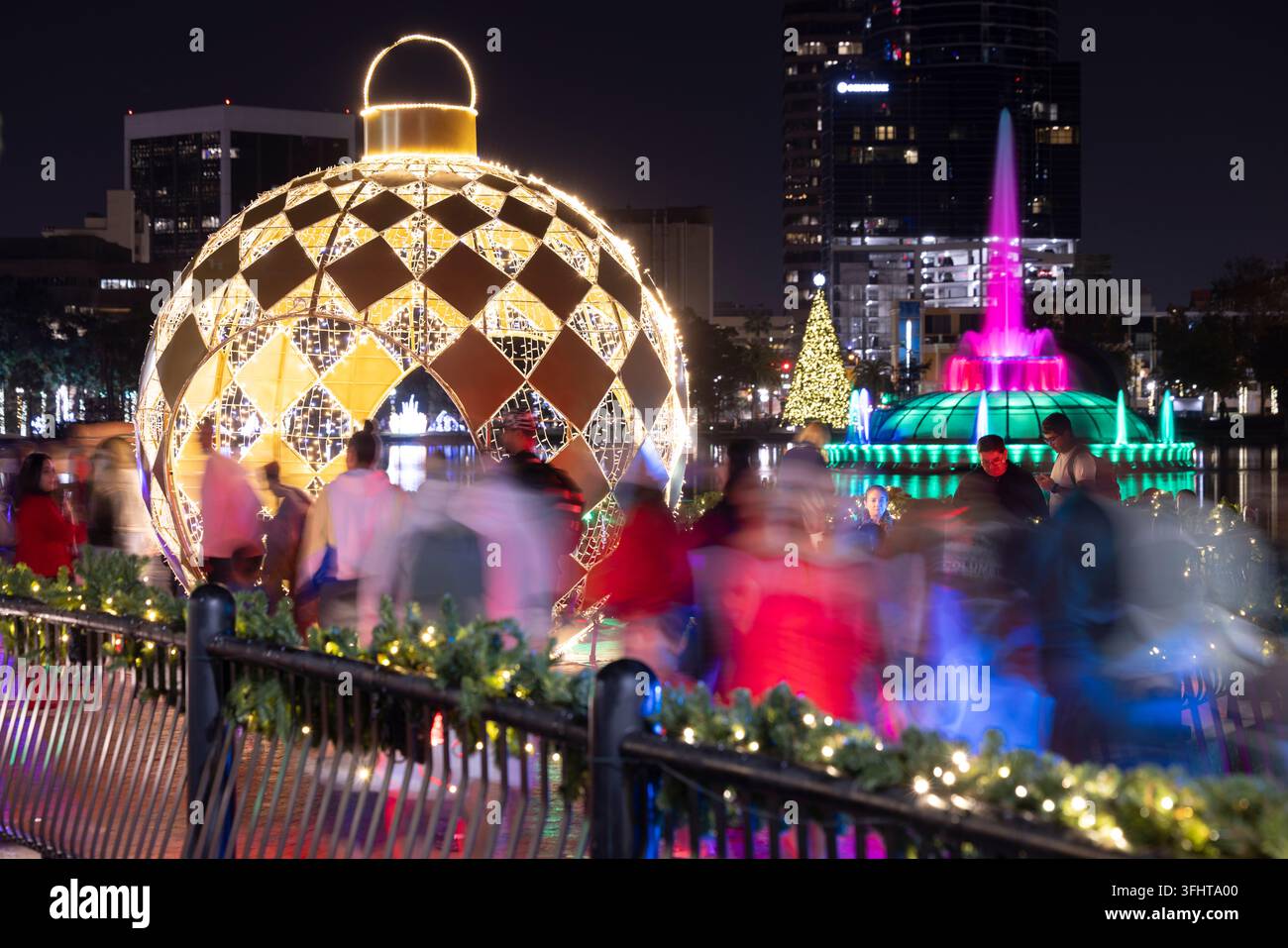 Orlando, Florida, USA - 23 dicembre 2025: Vista sfocata per il movimento di persone che camminano lungo le rive del Lake Eola nel centro città, decorate per le festività natalizie Foto Stock