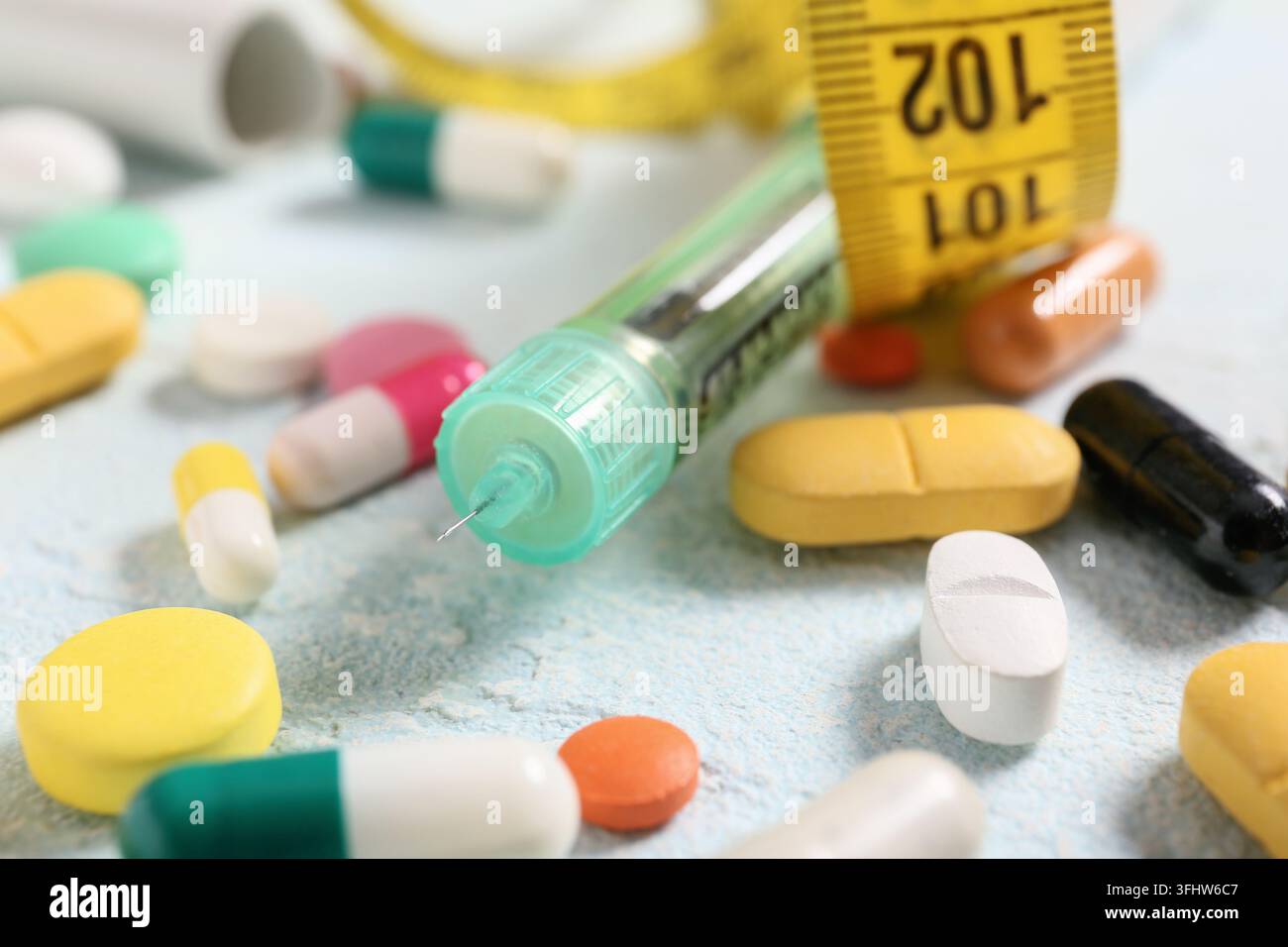 Gestione del diabete e terapia insulinica, siringa medica con nastro metrico e varie pillole farmaceutiche per il trattamento delle malattie croniche e la salute Foto Stock