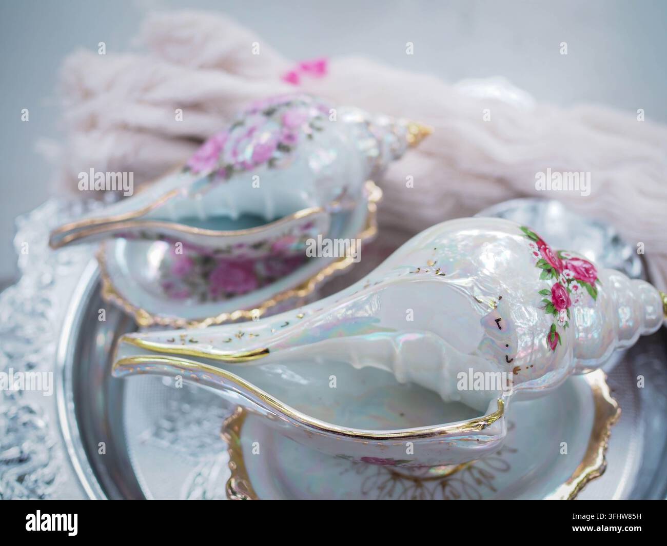 Conchiglie dipinte decorative con rose rosa su un vassoio d'argento Foto Stock