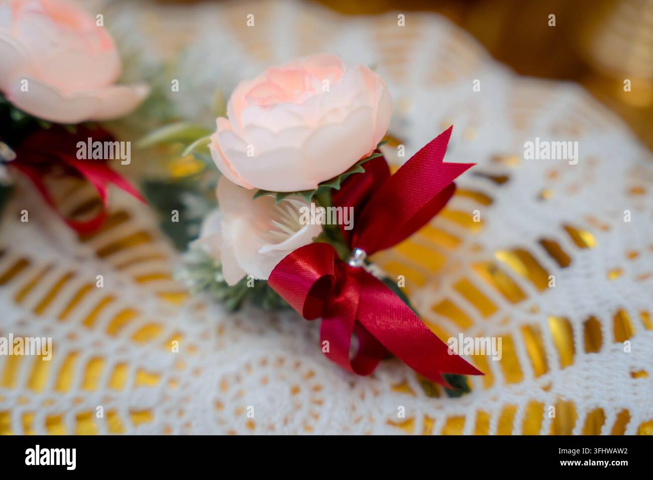 Bellissima boutonniera di rose rosa decorata con un nastro rosso per un matrimonio Foto Stock