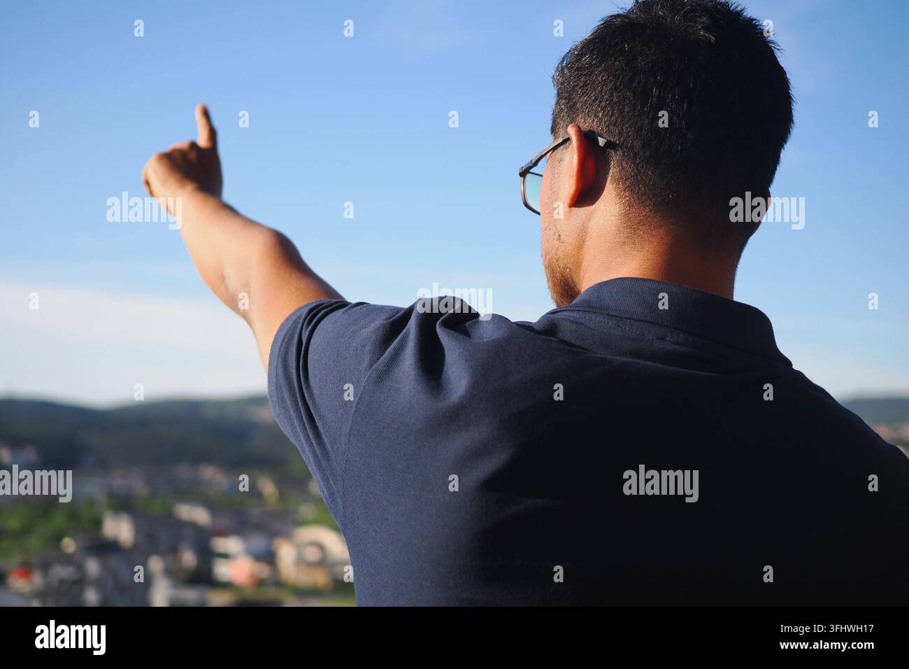 Un uomo indica il cielo mentre guarda un paesaggio cittadino Foto Stock
