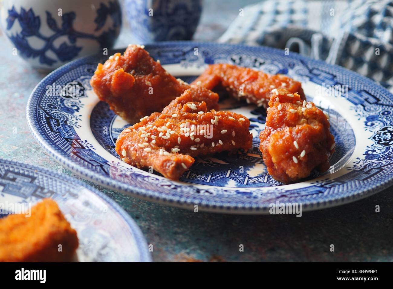Alette di pollo glassate al sesamo su piatto di porcellana blu pronte da servire come antipasto Foto Stock