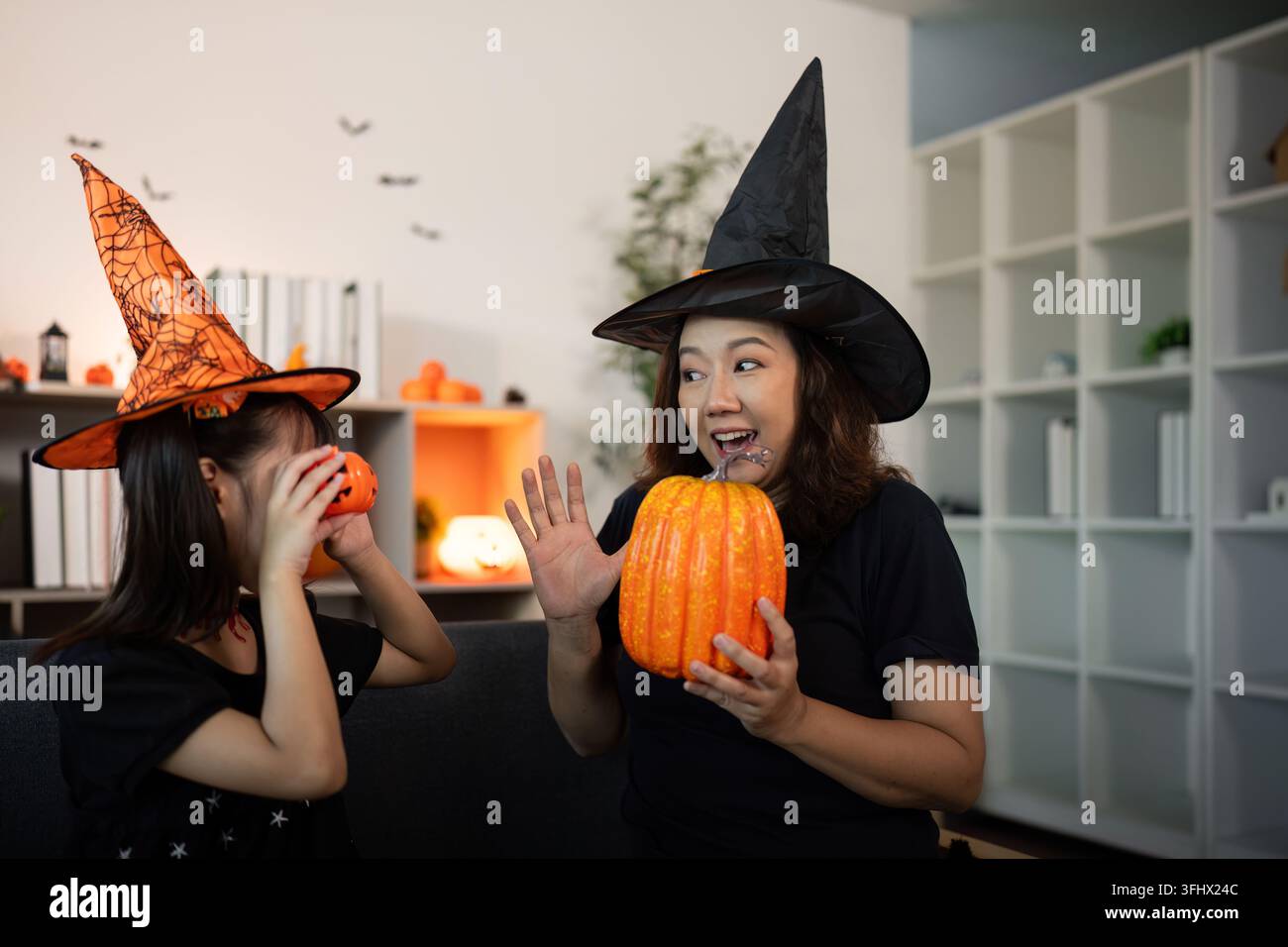 Festa di Halloween. Mamma e figlia si godono momenti festivi con zucche e cappelli da streghe. Foto Stock