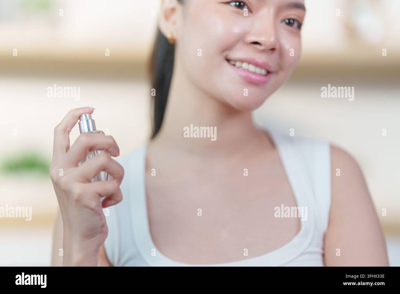 Donna asiatica che spruzza profumo sul collo per la fragranza e la routine di bellezza quotidiana Foto Stock