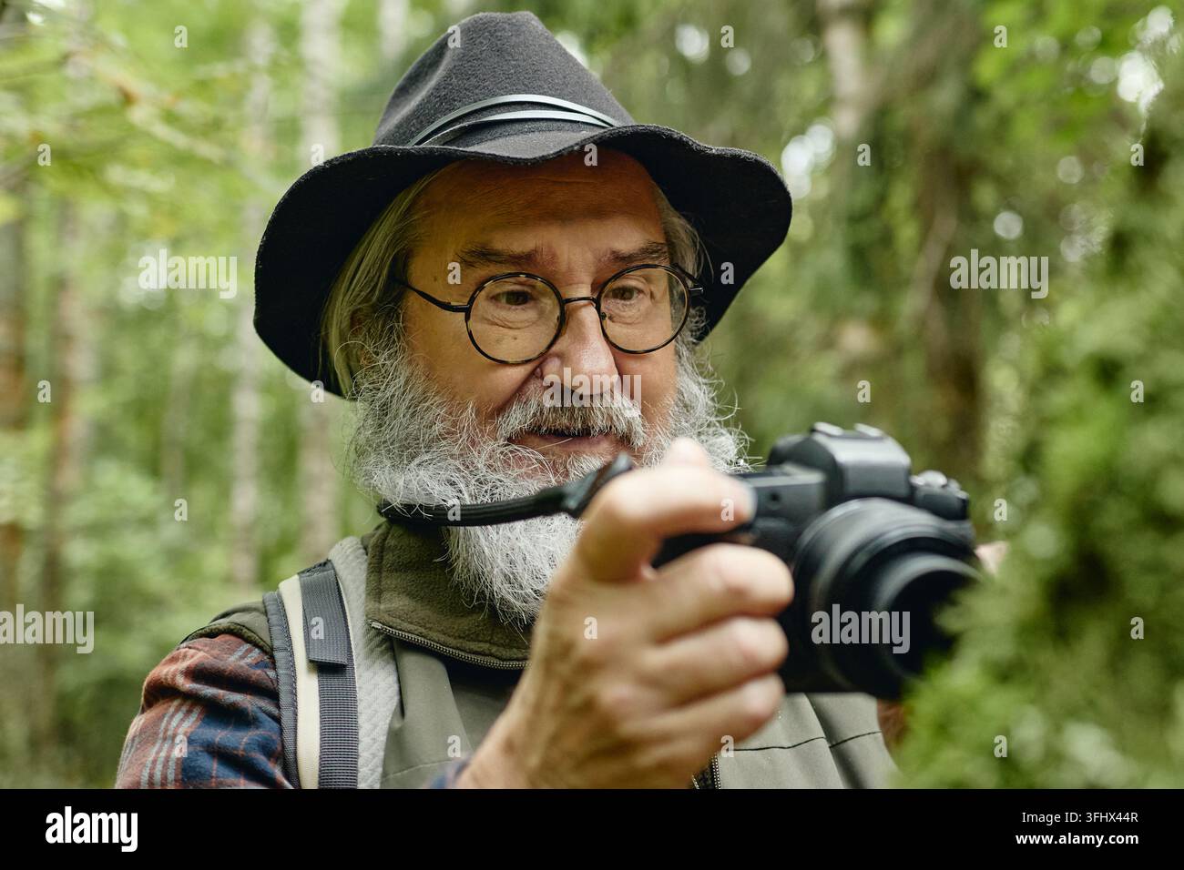 Uomo anziano che fotografa la natura con una fotocamera digitale all'aperto Foto Stock
