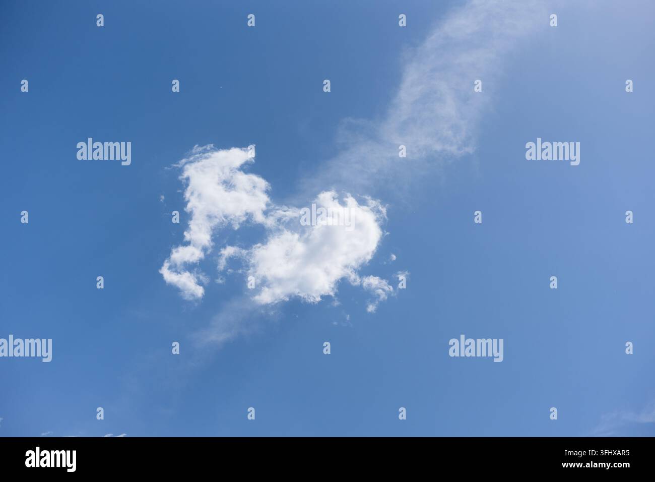 Una nuvola bianca a forma di cuore contro un cielo blu Foto Stock