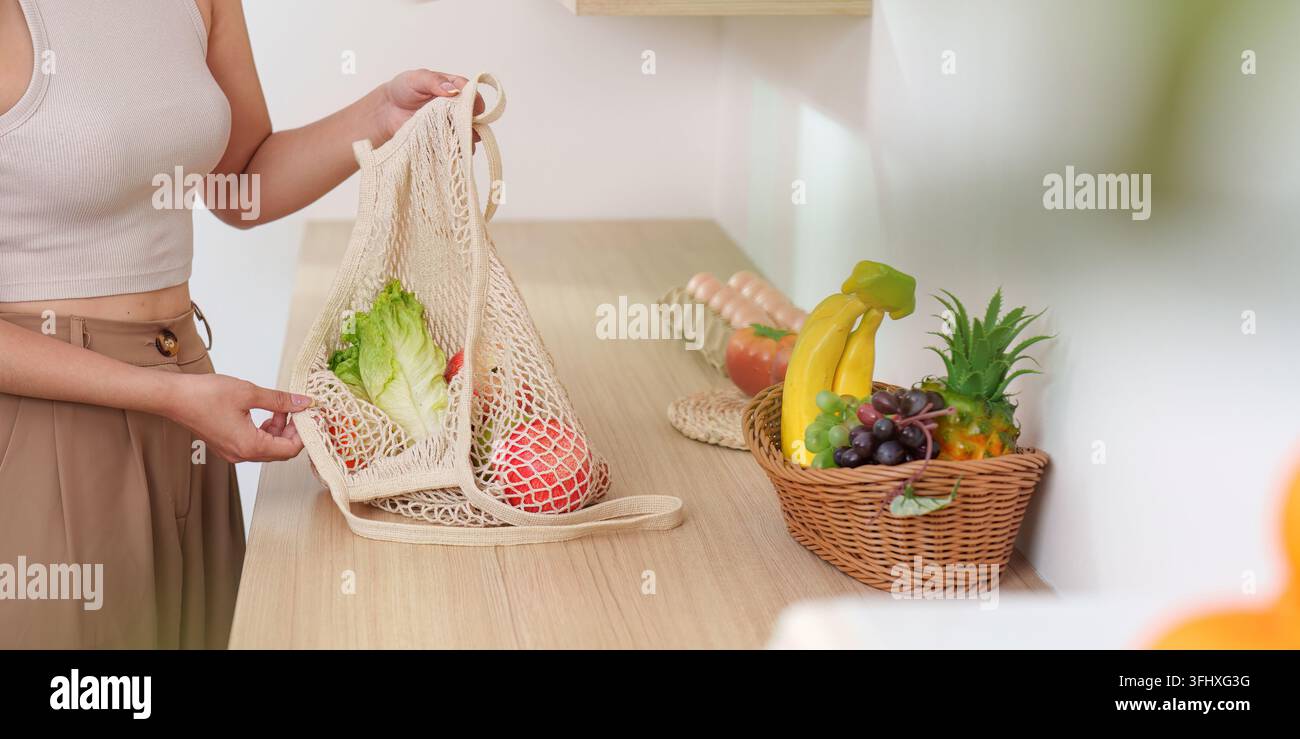 Scelte ecologiche: Donna che imballa i prodotti freschi in una borsa riutilizzabile Foto Stock
