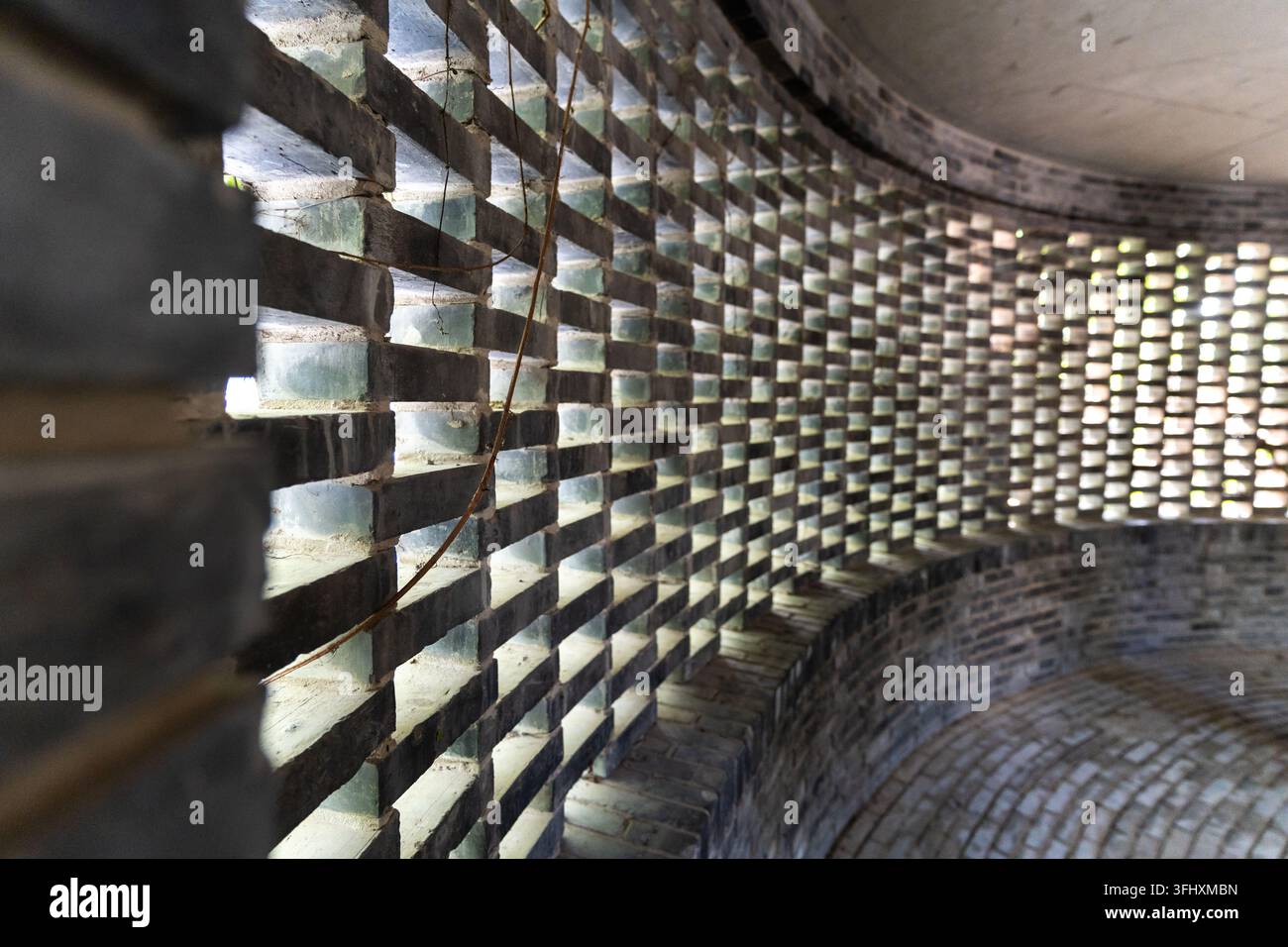 Muro di mattoni strutturato con ritagli curvi e luce e ombra screziate Foto Stock