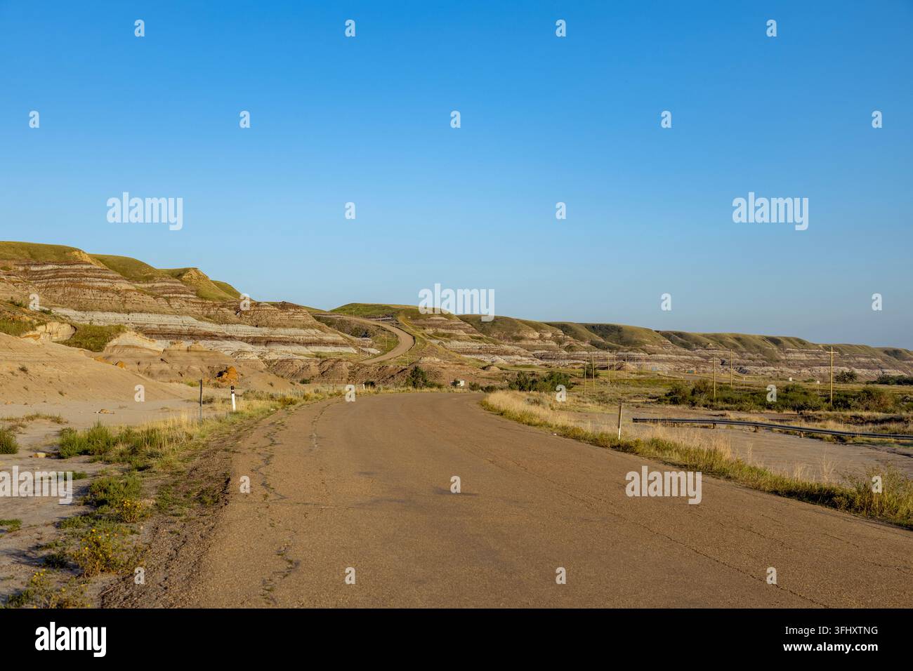 Strada panoramica si snoda attraverso badlands stratificati sotto un cielo blu terso, Drumheller, AB TOJ OYO , Alberta, Canada Foto Stock