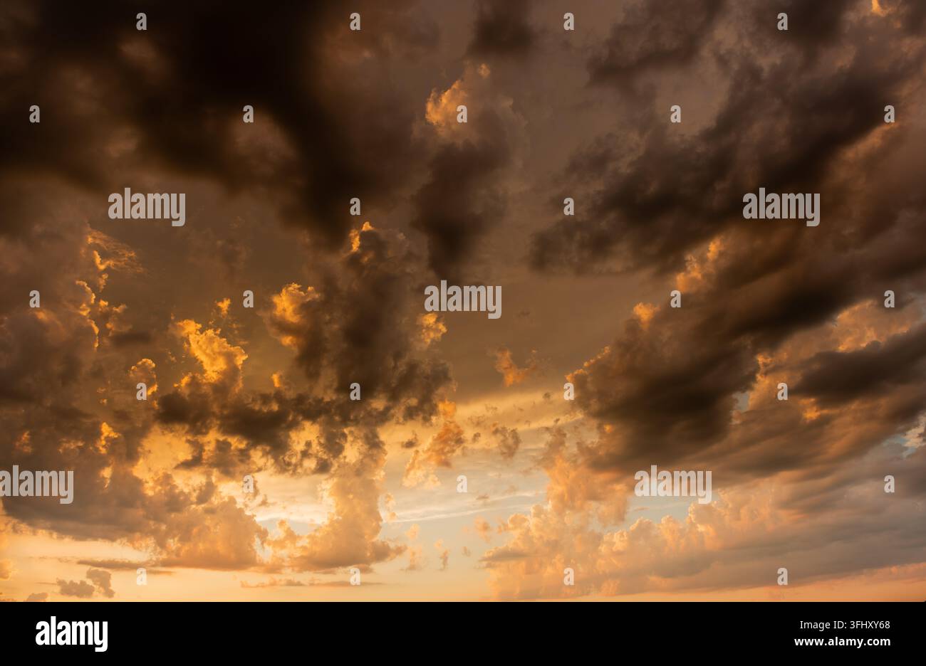 Drammatiche nuvole dorate creano uno spettacolo di tramonto mozzafiato sopra l'orizzonte durante le ore serali Foto Stock