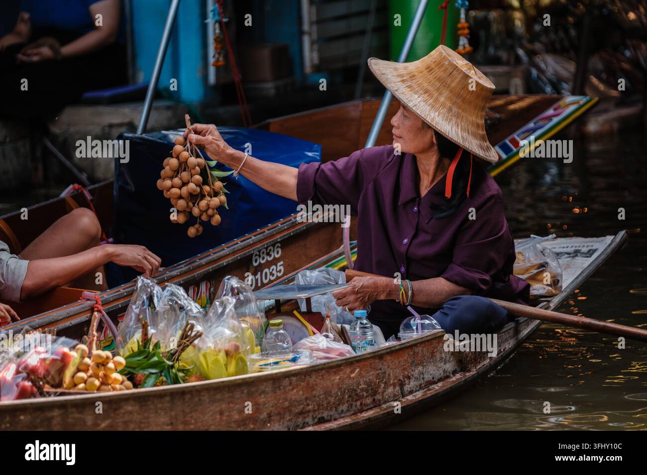 Esplora il vivace mercato galleggiante di Damnoen Saduak in Thailandia con vari prodotti locali Foto Stock