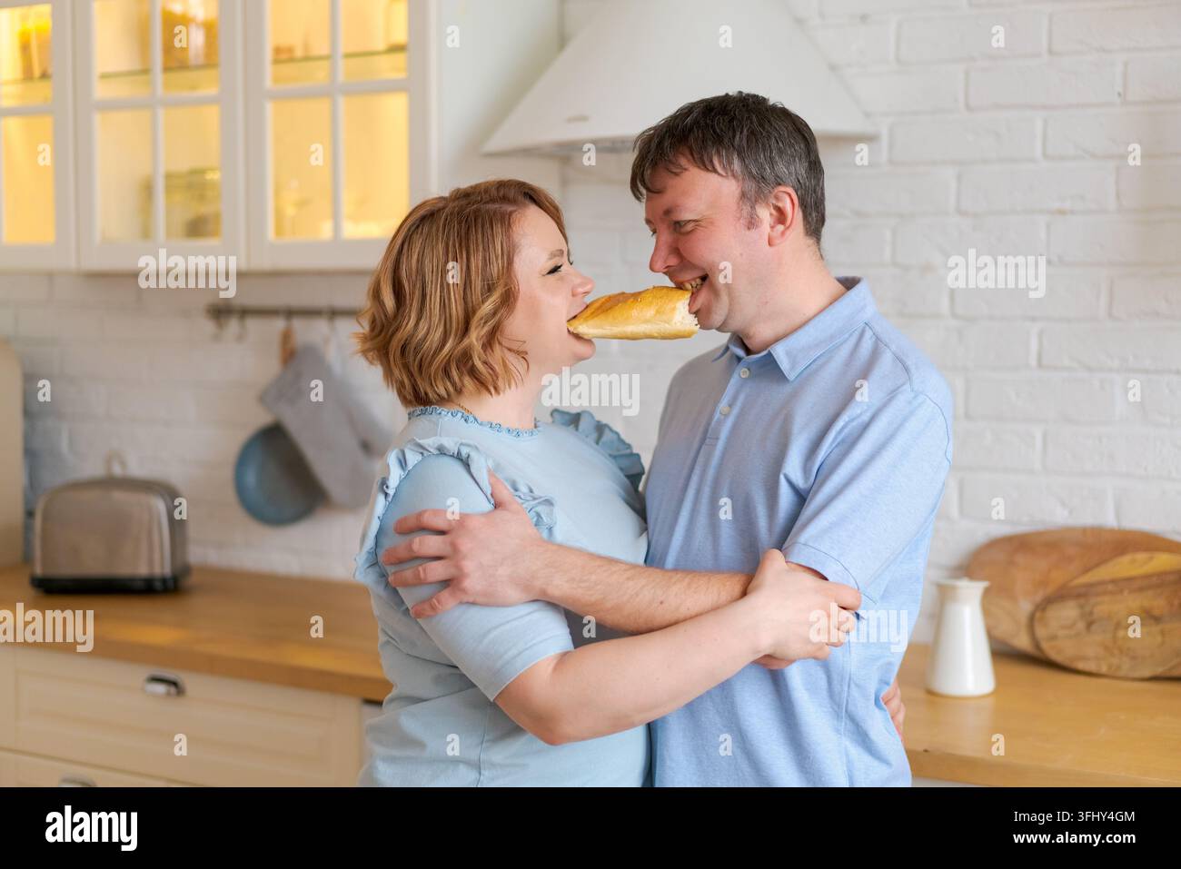 Una famiglia allegra in cucina, bambini che giocano a tavola e genitori che ballano Foto Stock