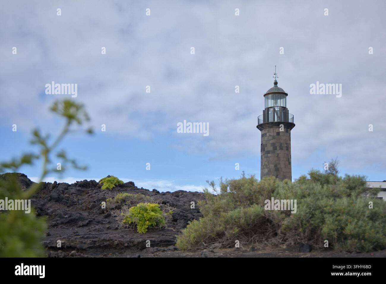 Faro storico in pietra Faro Viejo a Fuencaliente con primo piano sfocato della vegetazione costiera locale, La Palma, Isole Canarie Foto Stock