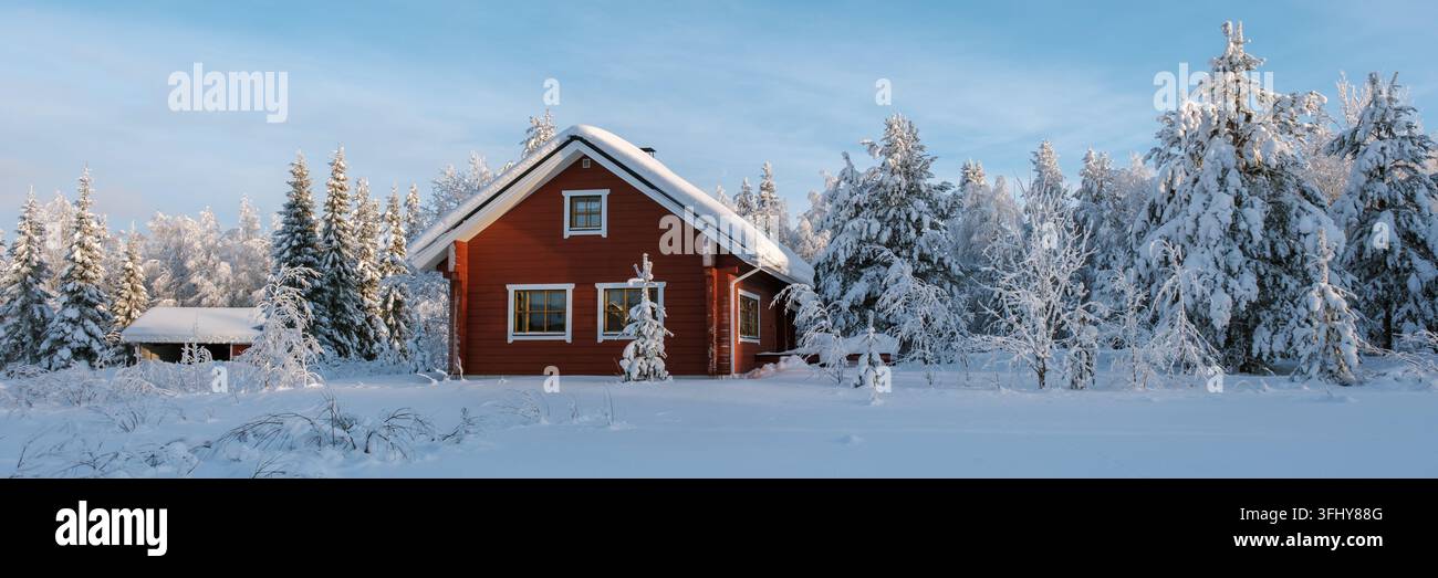 Provate la serenità di un'accogliente cabina rossa circondata da neve bianca incontaminata ad Akaslompolo, Lapponia. Gli alti alberi ricoperti di gelo creano una connessione wi-fi magica Foto Stock