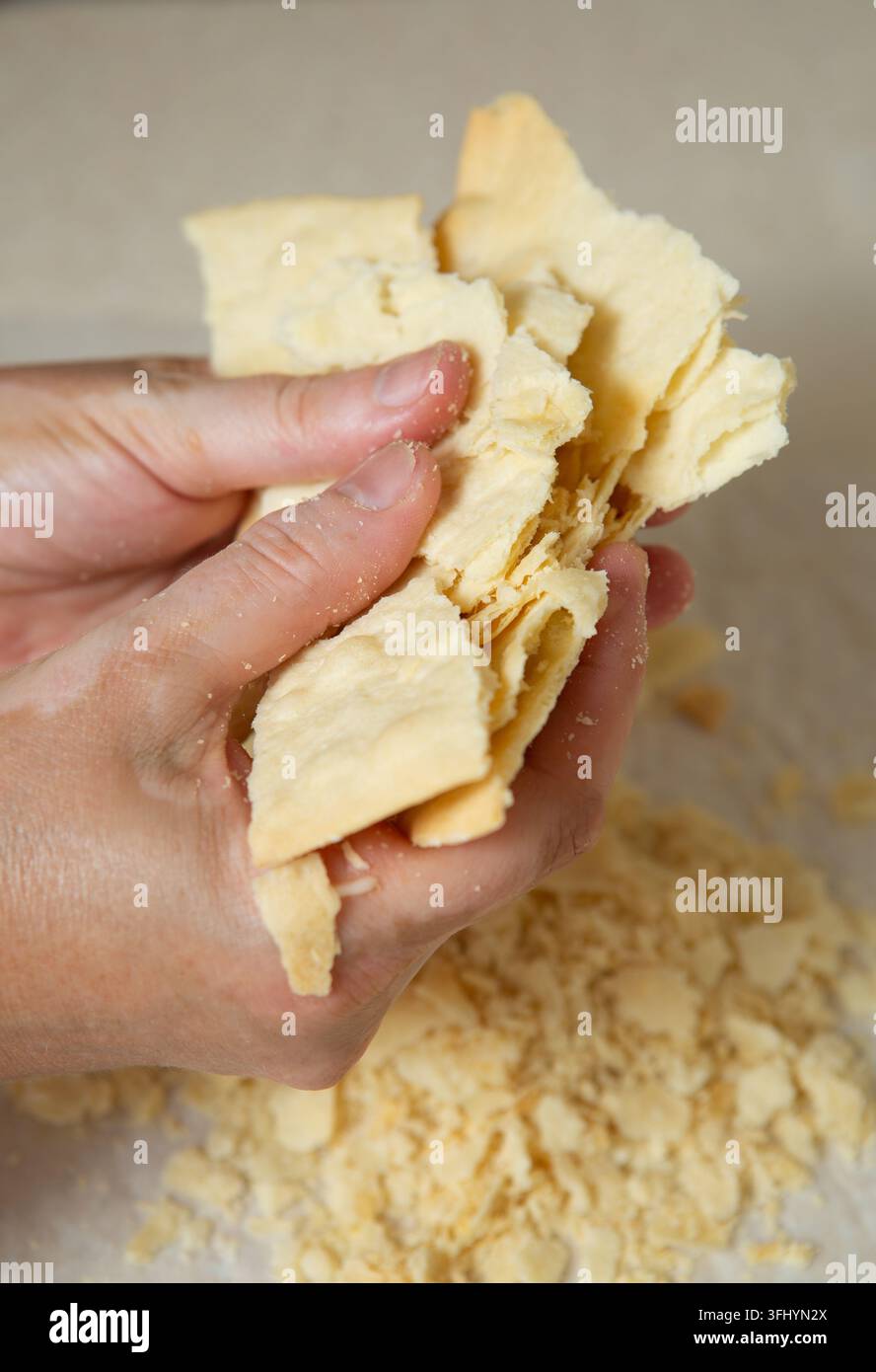 Preparazione di una torta Napoleone fatta in casa. Uno strato è rotto in piccoli pezzi per spolverare la torta Foto Stock