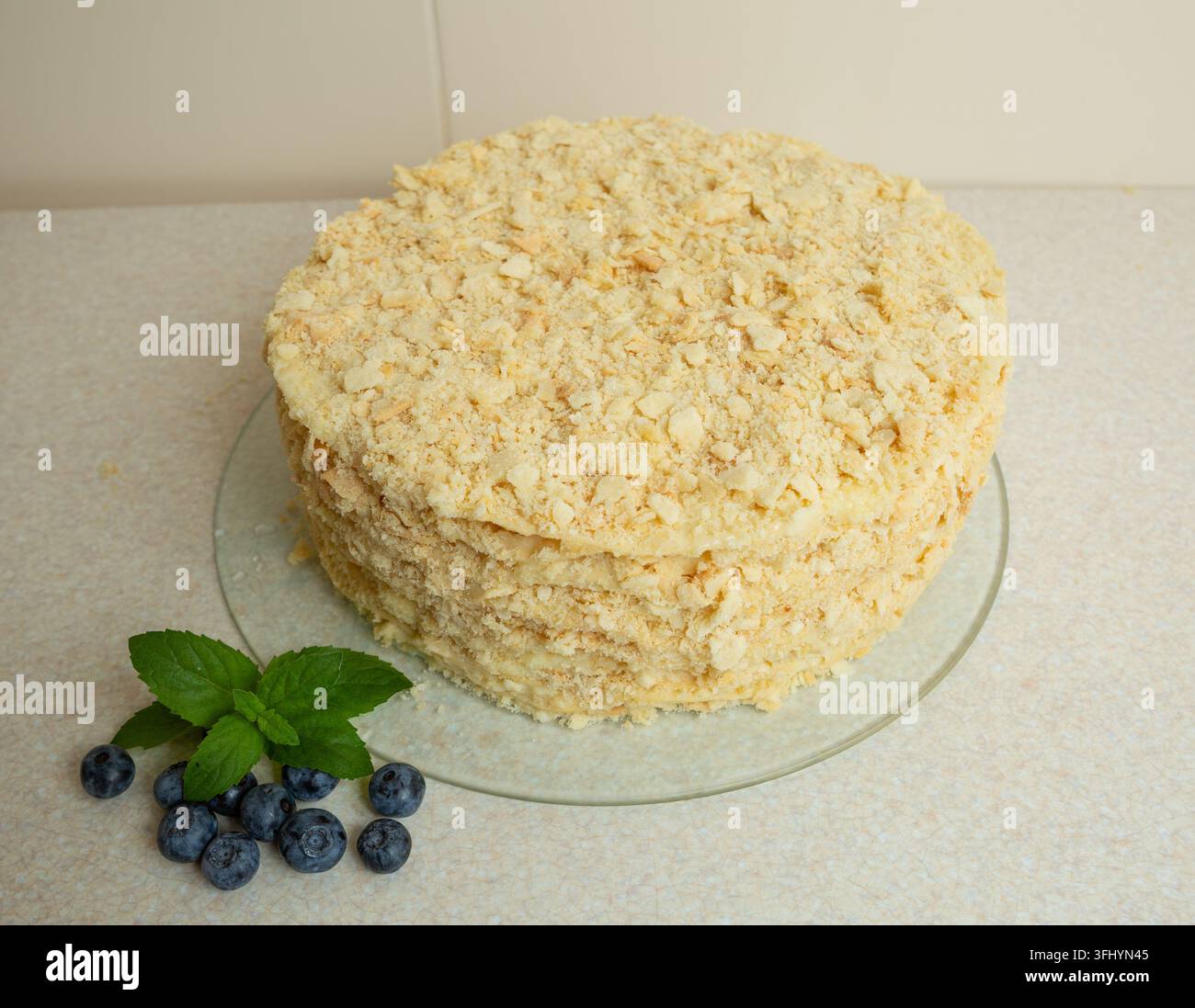 La torta Napoleone fatta in casa è sul tavolo. È decorata con foglie di menta e mirtilli Foto Stock