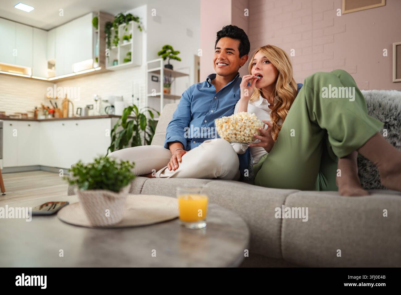 Coppia che si rilassa a casa guardando un film e mangiando popcorn Foto Stock