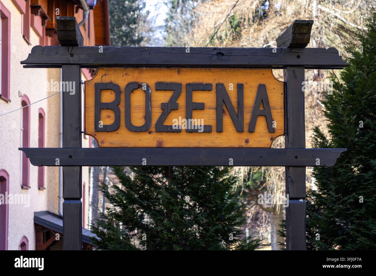 Szklarska Poręba, Polonia – 18 dicembre 2025: Una targhetta con nome Bozena incisa si trova all'interno di una struttura decorativa in legno marrone davanti a un tradizionale portico Foto Stock