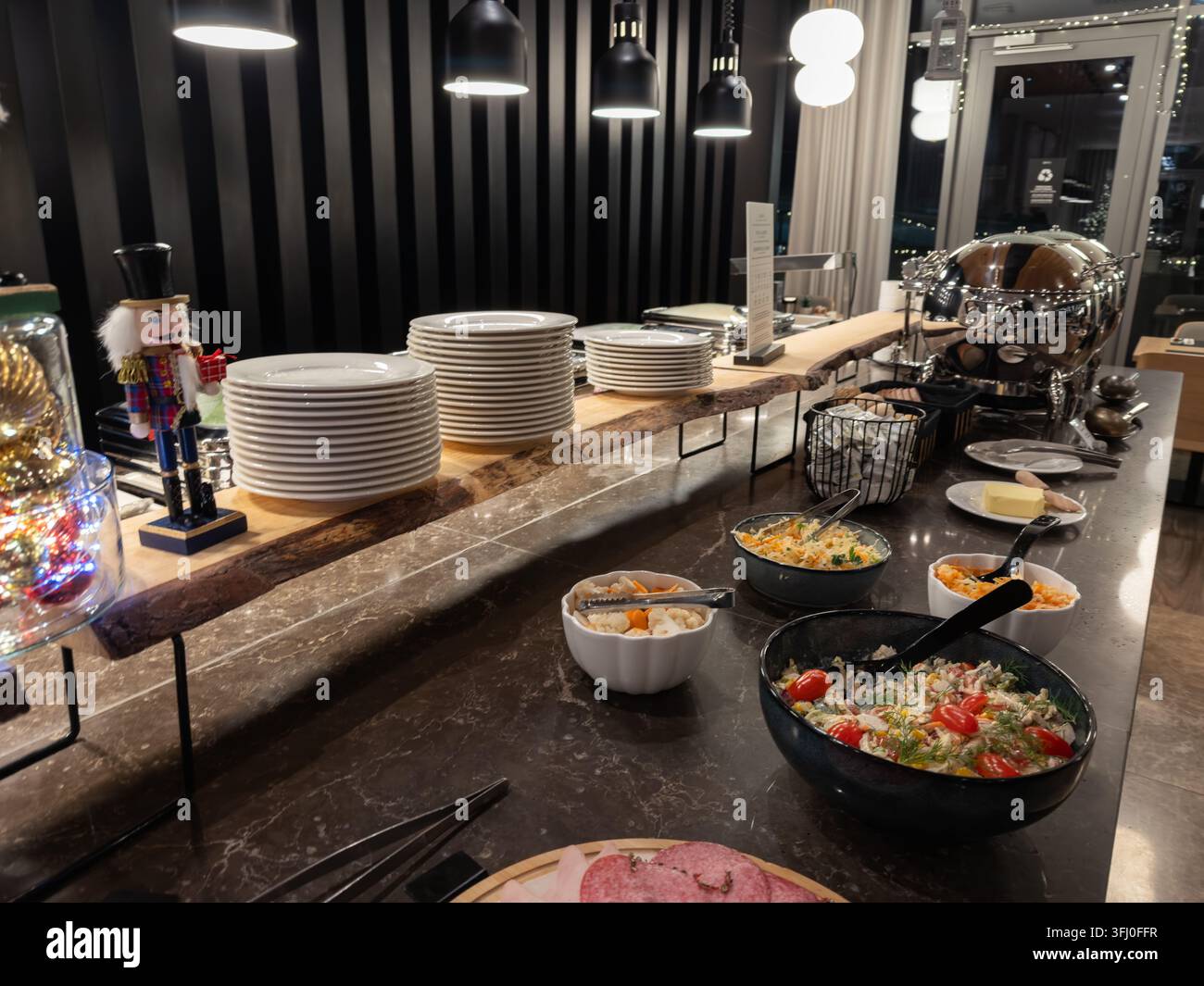 Disposizione elegante del buffet della colazione con pile di piatti bianchi, piatti salati e verdure colorate disposte su una superficie di marmo lucidata all'interno Foto Stock