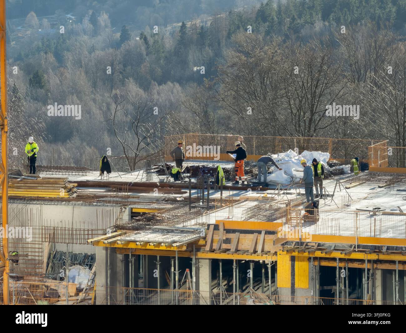 Lavoratori edili professionisti che costruiscono le fondamenta di una casa moderna circondata da alberi, evidenziando il lavoro industriale, l'ingegneria strutturale, a Foto Stock