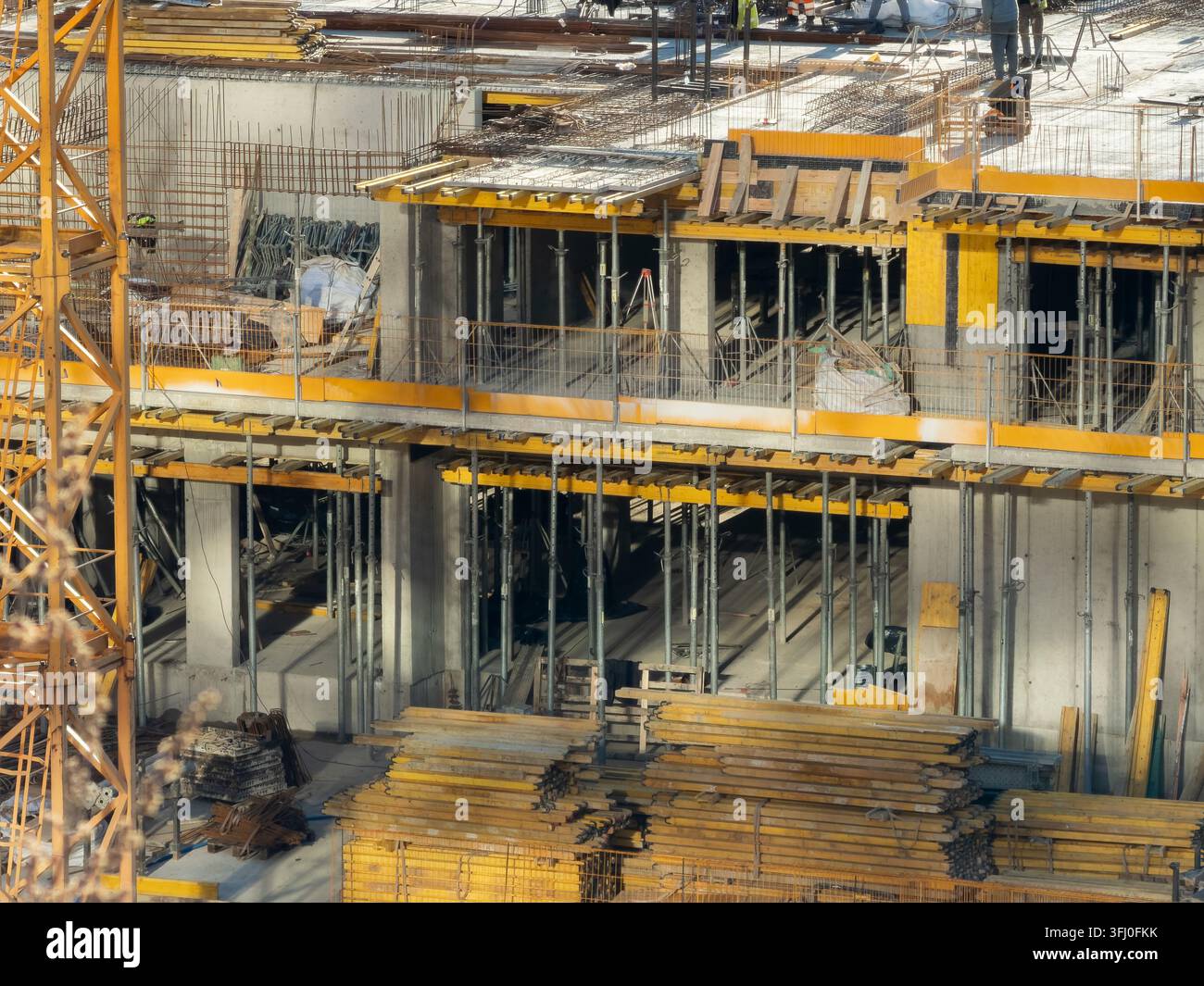 Strutture portanti in cemento con rinforzi in acciaio e pannelli di getto in legno si ergono in un cantiere affollato per illustrare lo sviluppo immobiliare moderno Foto Stock