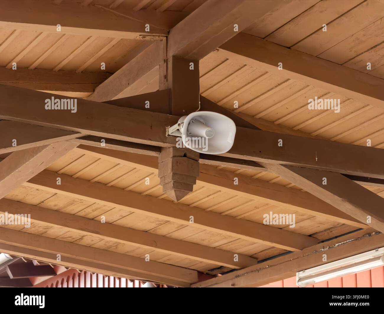 Il megfono PA attaccato alle travi di sostegno in legno pesante fornisce una copertura audio in un ambiente all'aperto, rappresentando sicurezza, trasmissione e notifica Foto Stock
