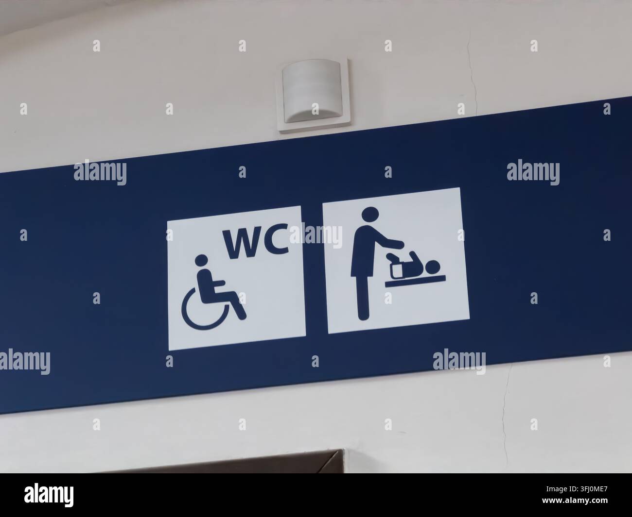 Segnaletta di un impianto pubblico con simboli per un bagno accessibile ai disabili e un'area per il cambio dei neonati, progettata per aiutare i visitatori a orientarsi Foto Stock