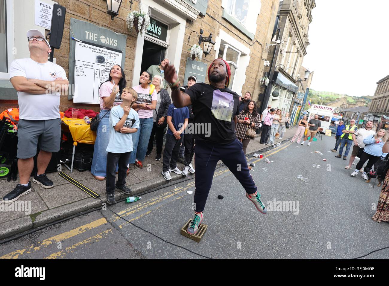 13 settembre 2026. Ramsbottom, Bury, Lancashire, Regno Unito. La Competizione Mondiale di Lancio del Black Pudding si svolge la seconda domenica di settembre all'Oaks Public House. I concorrenti si trovano su una 'Griglia Dorata', che viene ceremonialmente sfilata prima di essere posizionata davanti alla porta del pub. Tre black puddings fatti con sangue di maiale, rusk e grasso racchiusi in intestini vengono lanciati sotto mano su 12 Yorkshire Puddings su un plinto a 6 metri di altezza su un plinto di legno. Il vincitore è la persona che ne abbatte di più con 3 puddings. Quest'anno c'erano 4 vincitori ex aequo, tra cui la prima donna, e als Foto Stock