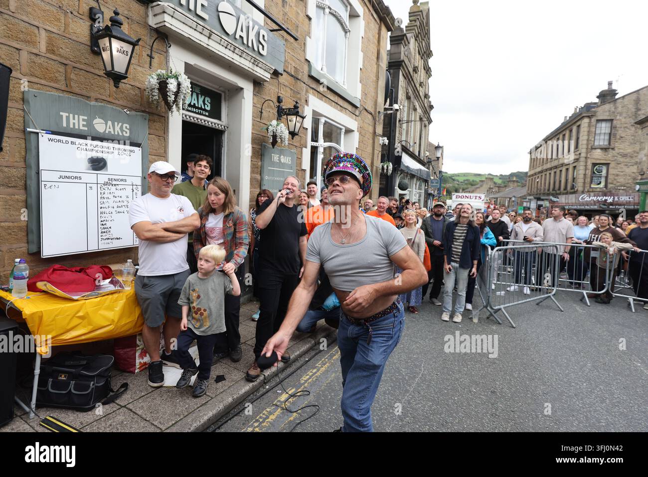 13 settembre 2026. Ramsbottom, Bury, Lancashire, Regno Unito. La Competizione Mondiale di Lancio del Black Pudding si svolge la seconda domenica di settembre all'Oaks Public House. I concorrenti si trovano su una 'Griglia Dorata', che viene ceremonialmente sfilata prima di essere posizionata davanti alla porta del pub. Tre black puddings fatti con sangue di maiale, rusk e grasso racchiusi in intestini vengono lanciati sotto mano su 12 Yorkshire Puddings su un plinto a 6 metri di altezza su un plinto di legno. Il vincitore è la persona che ne abbatte di più con 3 puddings. Quest'anno c'erano 4 vincitori ex aequo, tra cui la prima donna, e als Foto Stock