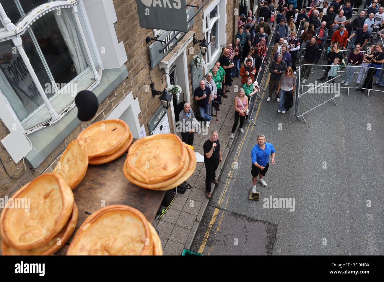 13 settembre 2026. Ramsbottom, Bury, Lancashire, Regno Unito. La Competizione Mondiale di Lancio del Black Pudding si svolge la seconda domenica di settembre all'Oaks Public House. I concorrenti si trovano su una 'Griglia Dorata', che viene ceremonialmente sfilata prima di essere posizionata davanti alla porta del pub. Tre black puddings fatti con sangue di maiale, rusk e grasso racchiusi in intestini vengono lanciati sotto mano su 12 Yorkshire Puddings su un plinto a 6 metri di altezza su un plinto di legno. Il vincitore è la persona che ne abbatte di più con 3 puddings. Quest'anno c'erano 4 vincitori ex aequo, tra cui la prima donna, e als Foto Stock