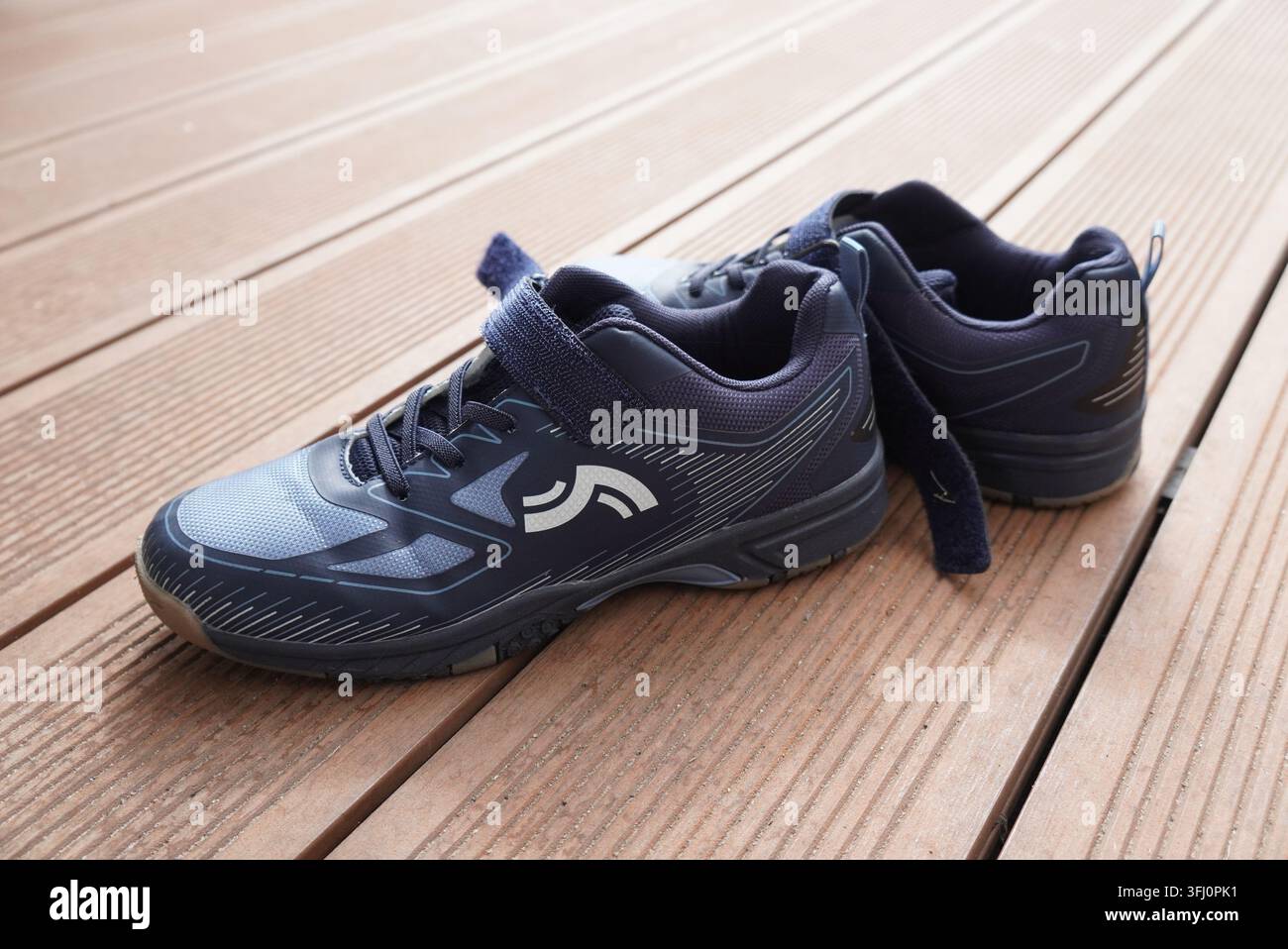 Queste scarpe sportive moderne per giovani presentano un design in mesh resistente e comode chiusure a strappo per un facile indossamento su una superficie esterna ruvida Foto Stock