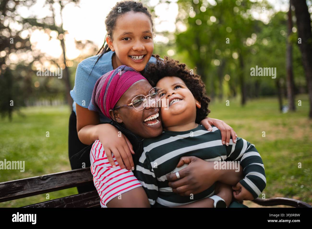 Famosa famiglia afroamericana che ride e si abbraccia nel parco Foto Stock