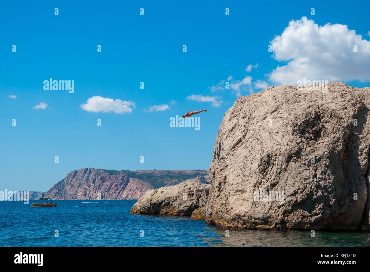 Uomo caucasico che si tuffa da un alto scoglio nelle acque del Mar Nero – Avventura in Crimea Foto Stock