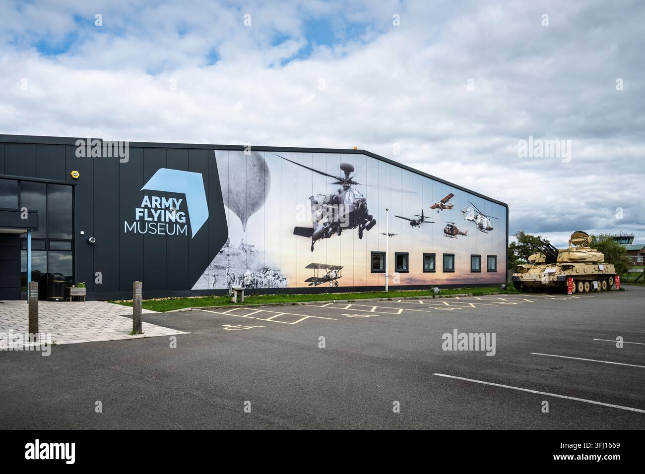 La facciata esterna dell'edificio del Museo Volante dell'Esercito a Middle Wallop nell'Hampshire, Regno Unito, con un grande murale di aerei e un carro militare Foto Stock