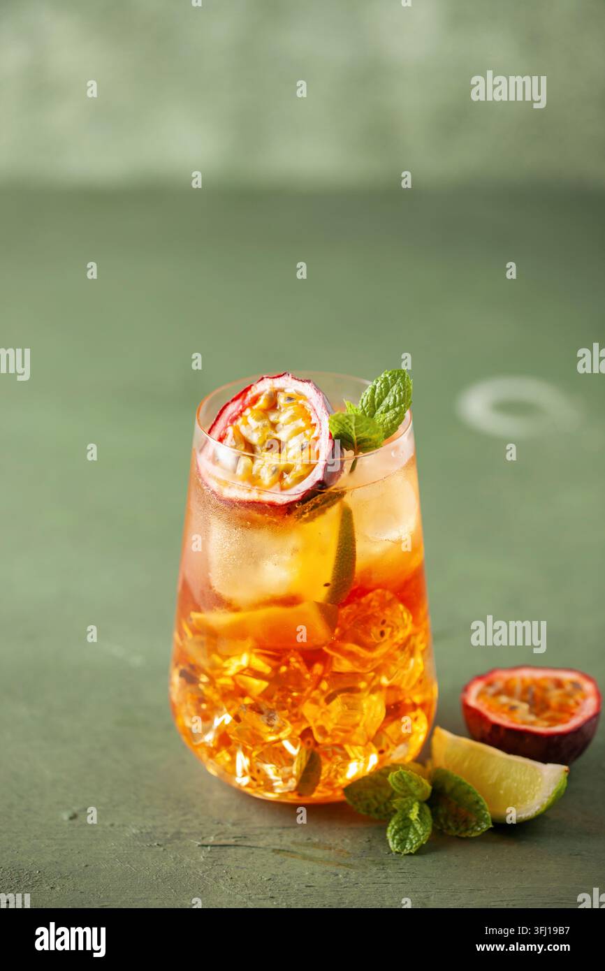 Tè con ghiaccio alla frutta. Rinfrescante bevanda estiva con sciroppo, frutto della passione, lime, menta e ghiaccio. Bicchiere con bevanda fresca e salutare Foto Stock