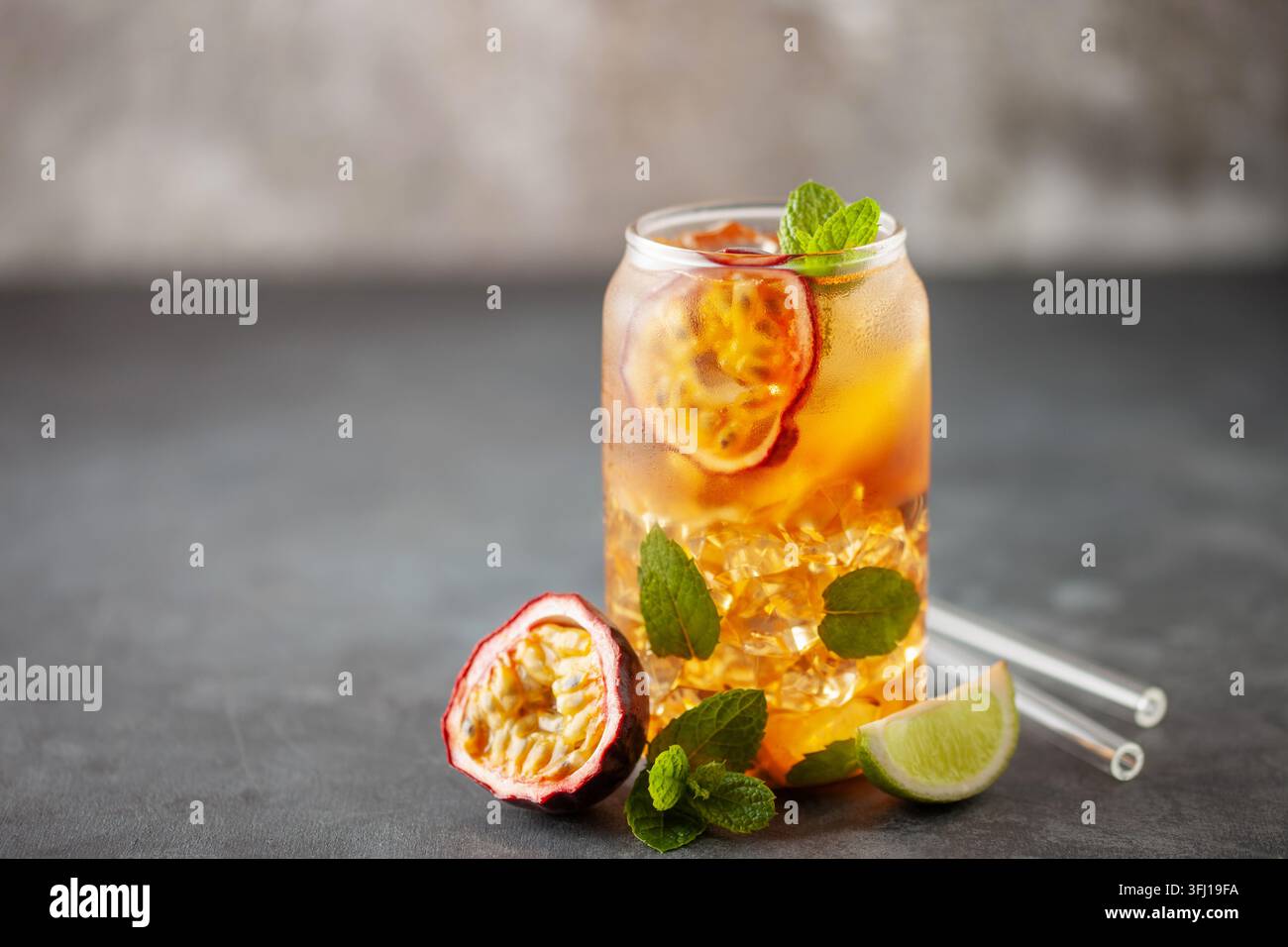Tè con ghiaccio alla frutta. Rinfrescante bevanda estiva con sciroppo, frutto della passione, lime, menta e ghiaccio. Bicchiere con bevanda fresca e salutare Foto Stock