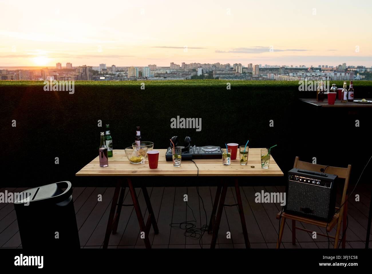Attrezzature per DJ e bevande sul tavolo durante una festa sul tetto al tramonto Foto Stock