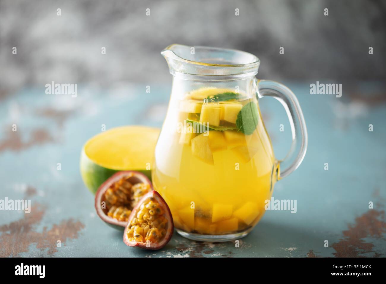 Tè freddo alla frutta con mango, frutto della passione e menta in una tazza di vetro sul tavolo. Foto Stock