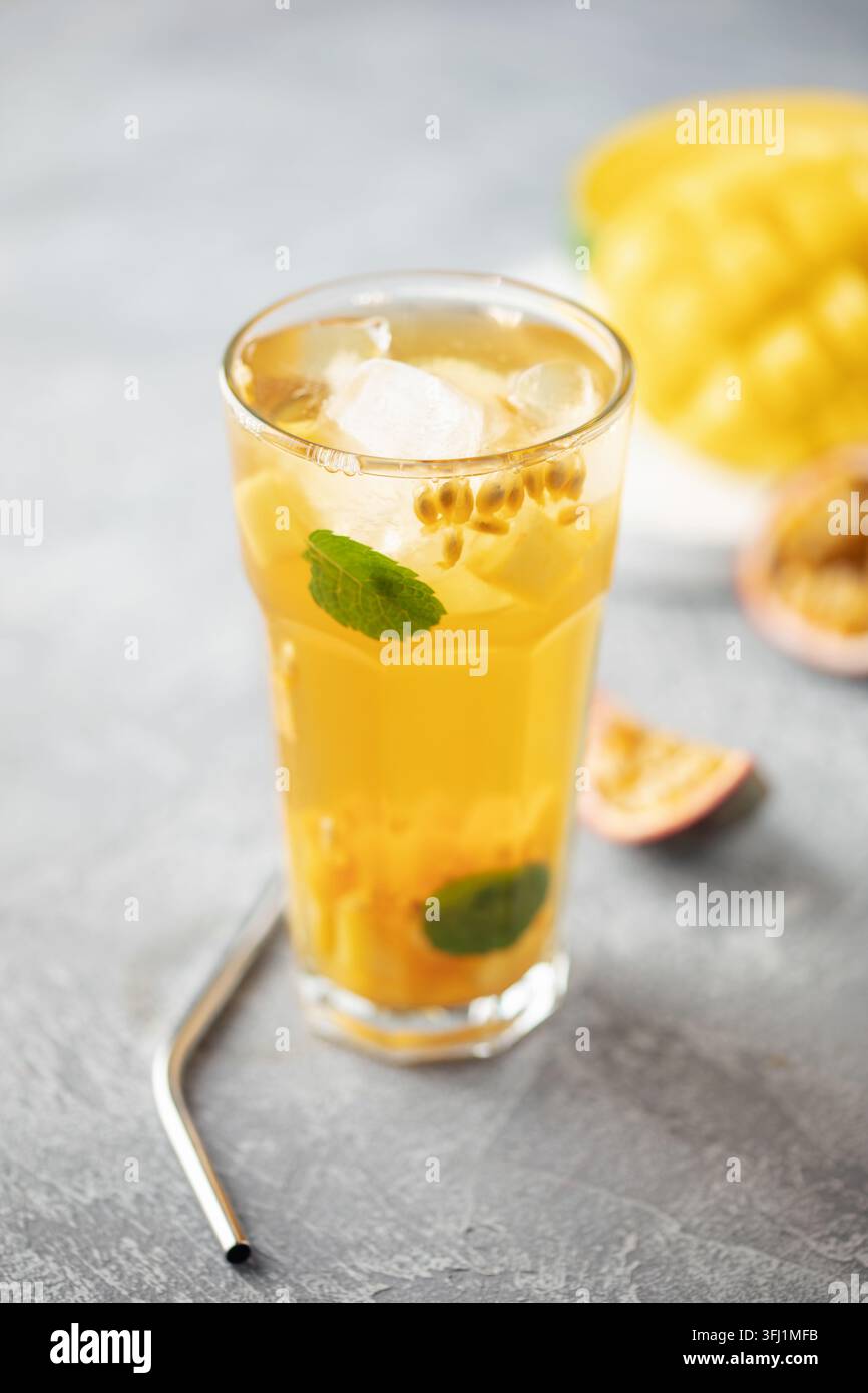Tè freddo alla frutta con mango, frutto della passione e menta in una tazza di vetro sul tavolo. Foto Stock