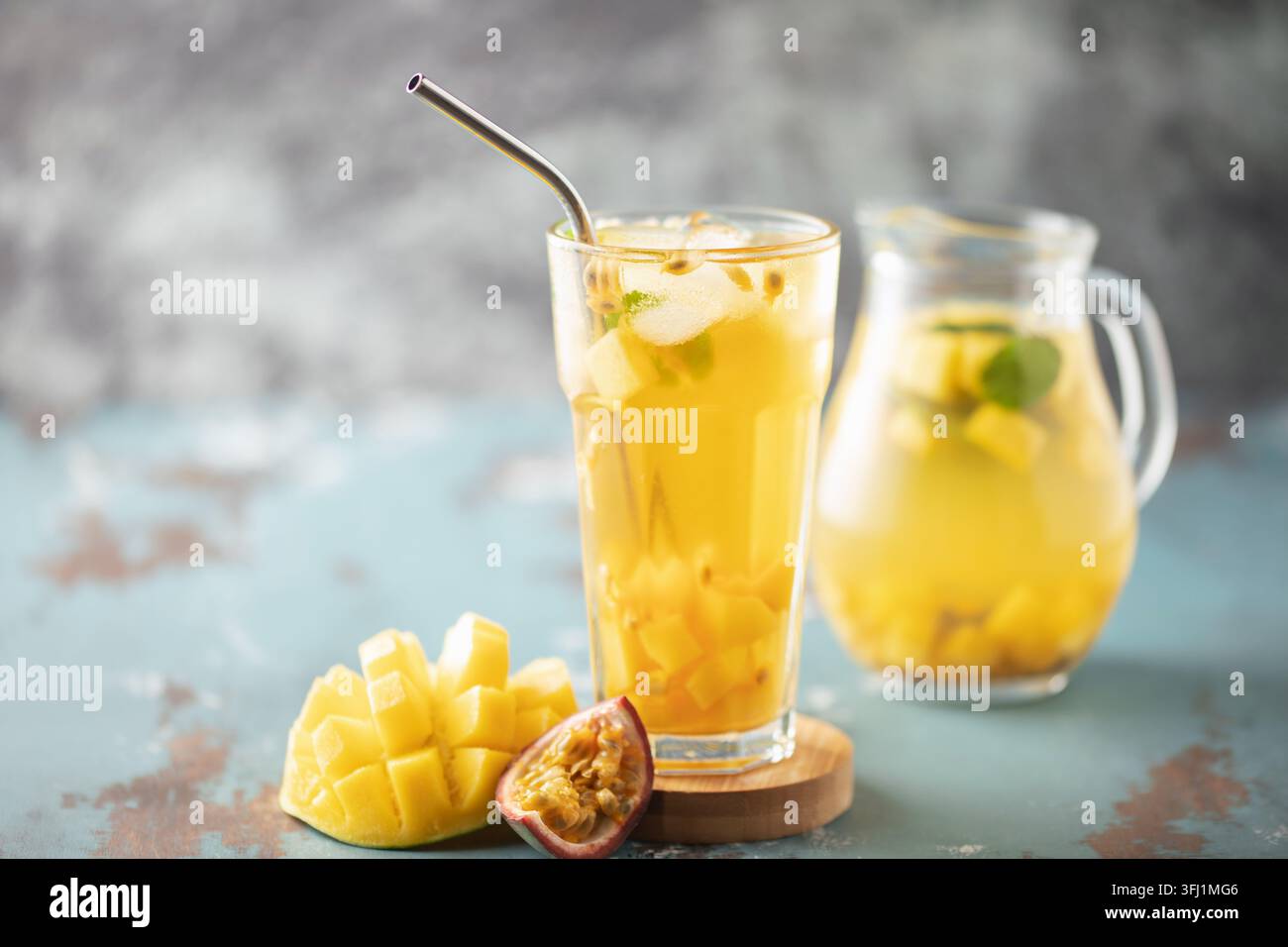 Tè freddo alla frutta con mango, frutto della passione e menta in una tazza di vetro sul tavolo. Foto Stock