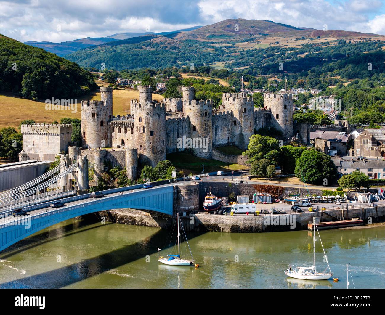 Castello di Conwy e ponti storici che attraversano il fiume Conwy, Galles del Nord, fortezza in pietra medievale che si erge sopra l'estuario con montagne sullo sfondo Foto Stock