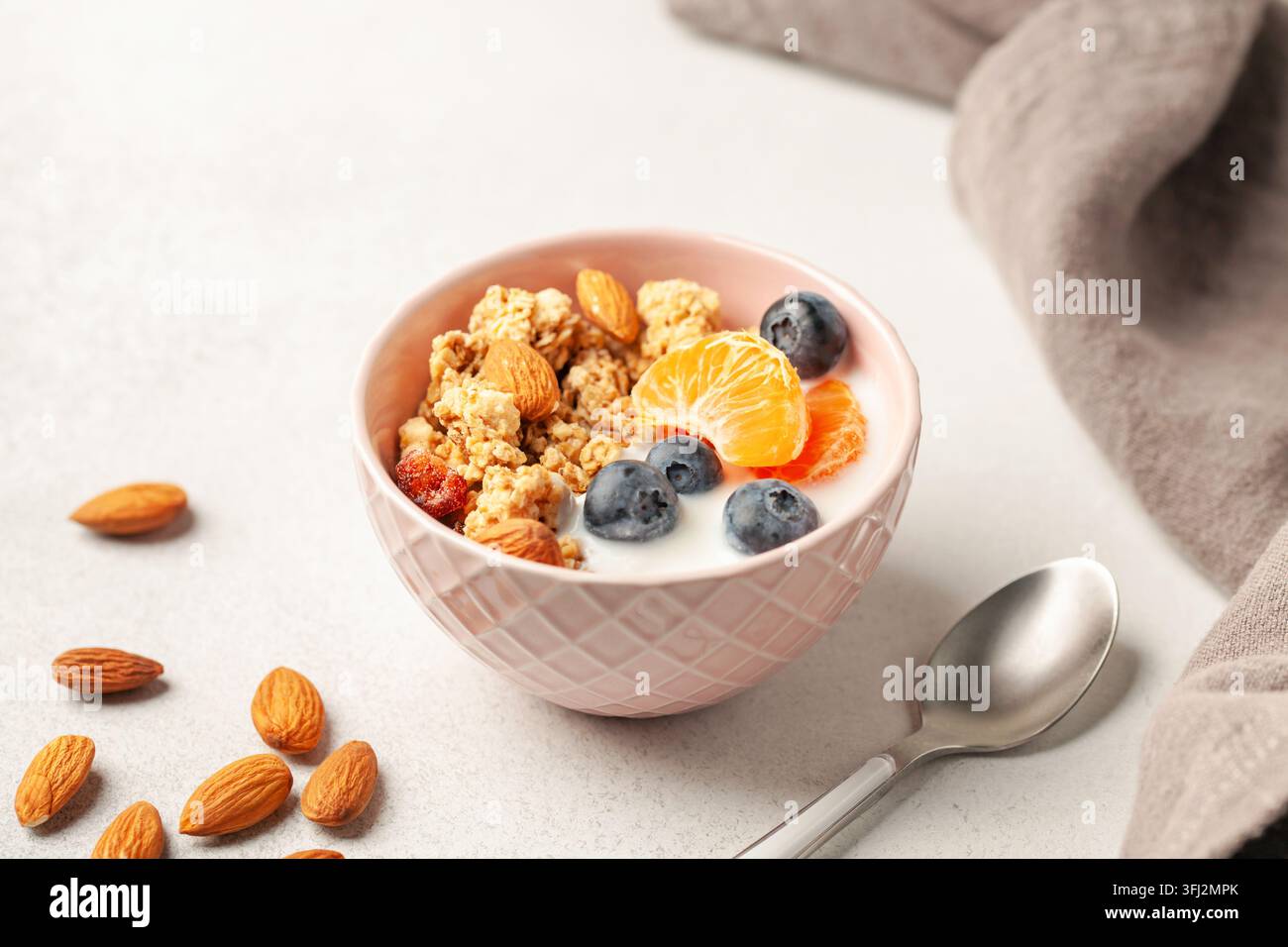 Muesli con farinata d'avena, yogurt, frutti di bosco, frutta e noci in un recipiente sul tavolo. Colazione salutare Foto Stock