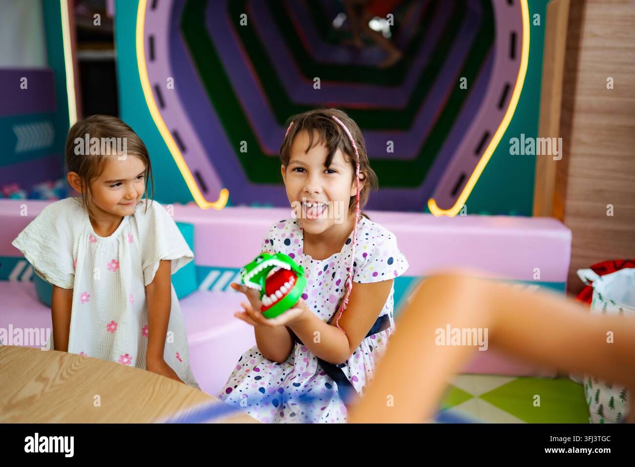 Ragazze che giocano a un gioco di giocattoli ridendo in un parco giochi al coperto Foto Stock