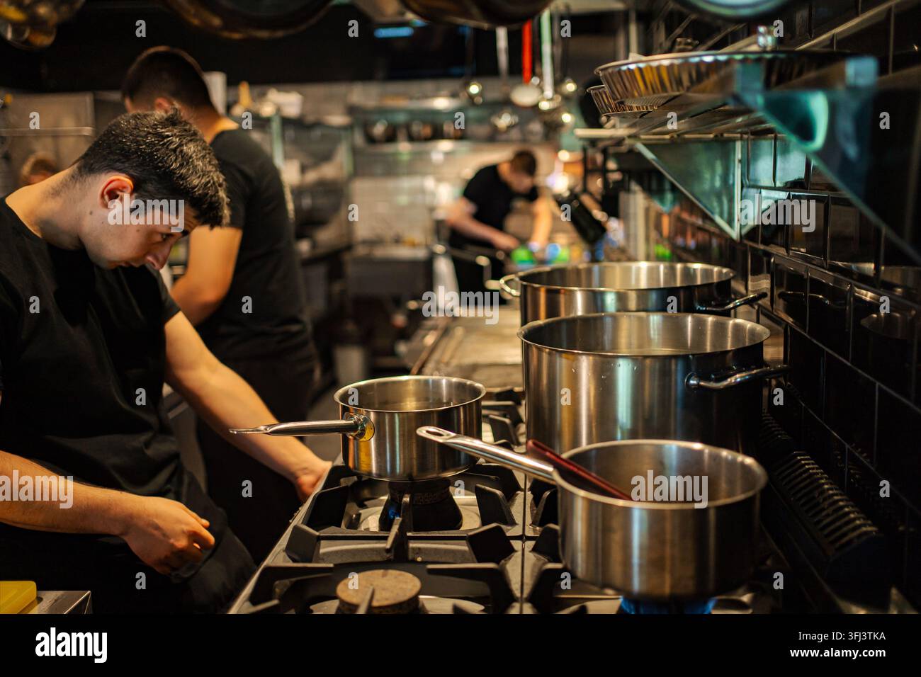 Chef professionisti al lavoro in una cucina di ristorante affollata Foto Stock