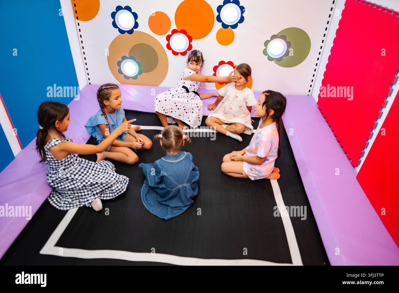 Ragazze che giocano a un gioco con gli occhi coperti in un parco giochi interno colorato Foto Stock