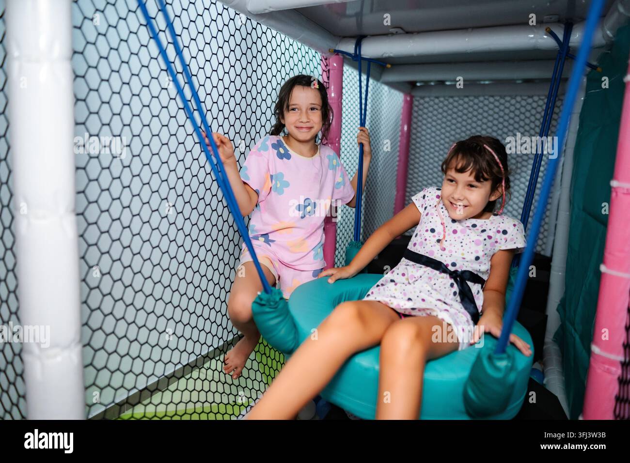 Ragazze che giocano sorridendo in un parco giochi interno colorato Foto Stock