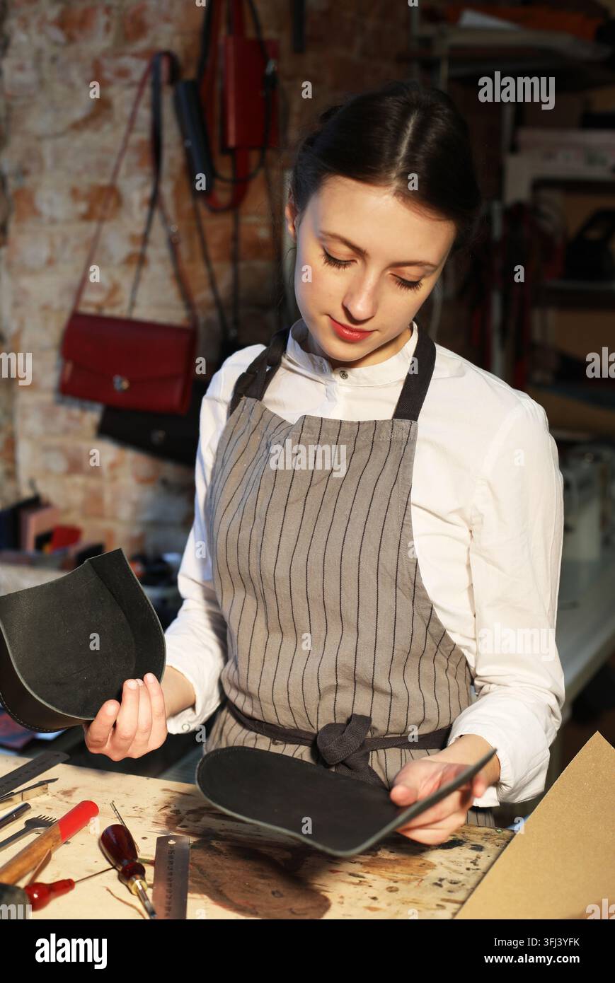 giovane donna bruna lavora in uno studio di produzione di borse, ritaglia dettagli Foto Stock