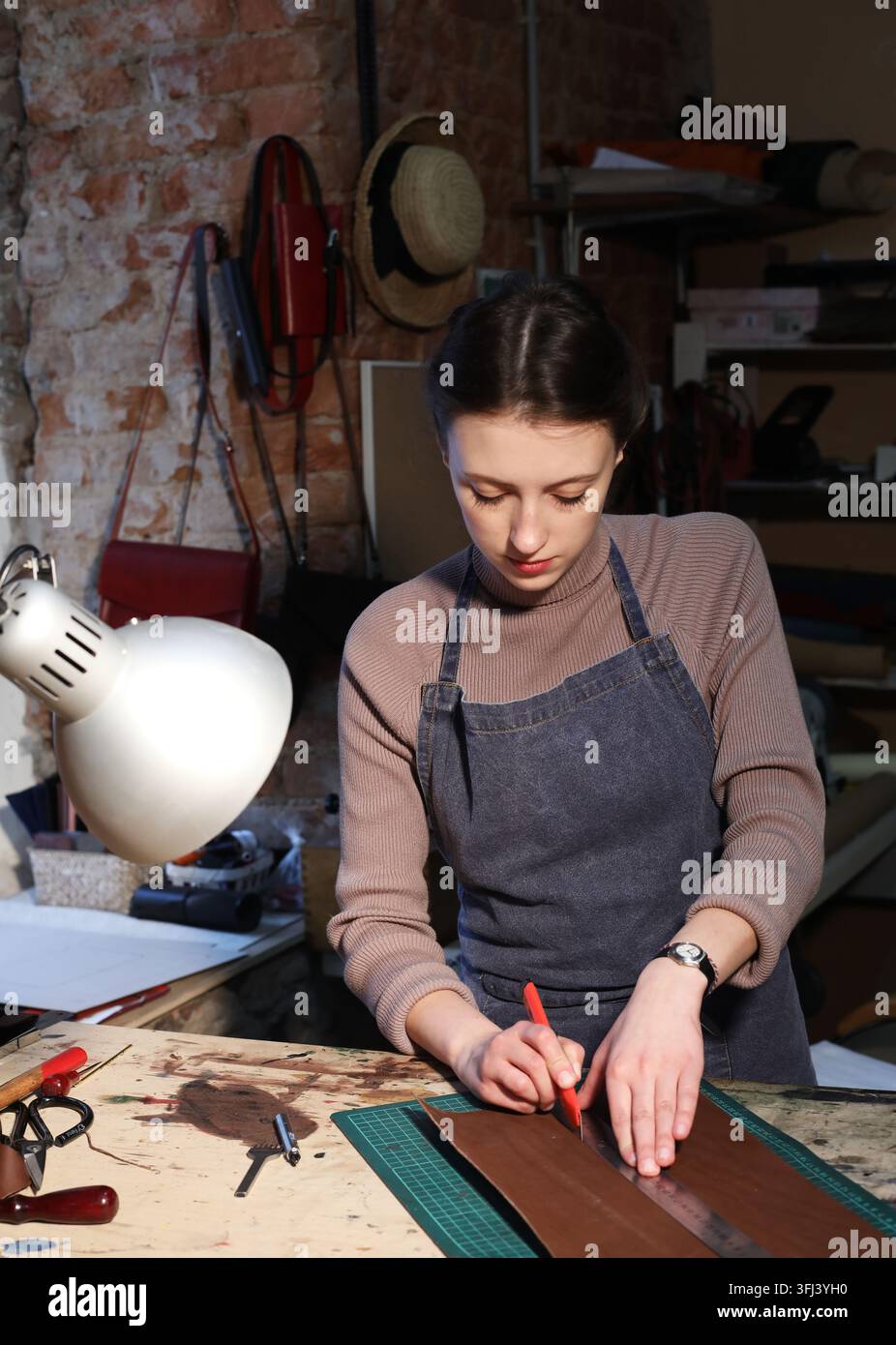 giovane donna bruna lavora in uno studio di produzione di borse, ritaglia dettagli Foto Stock