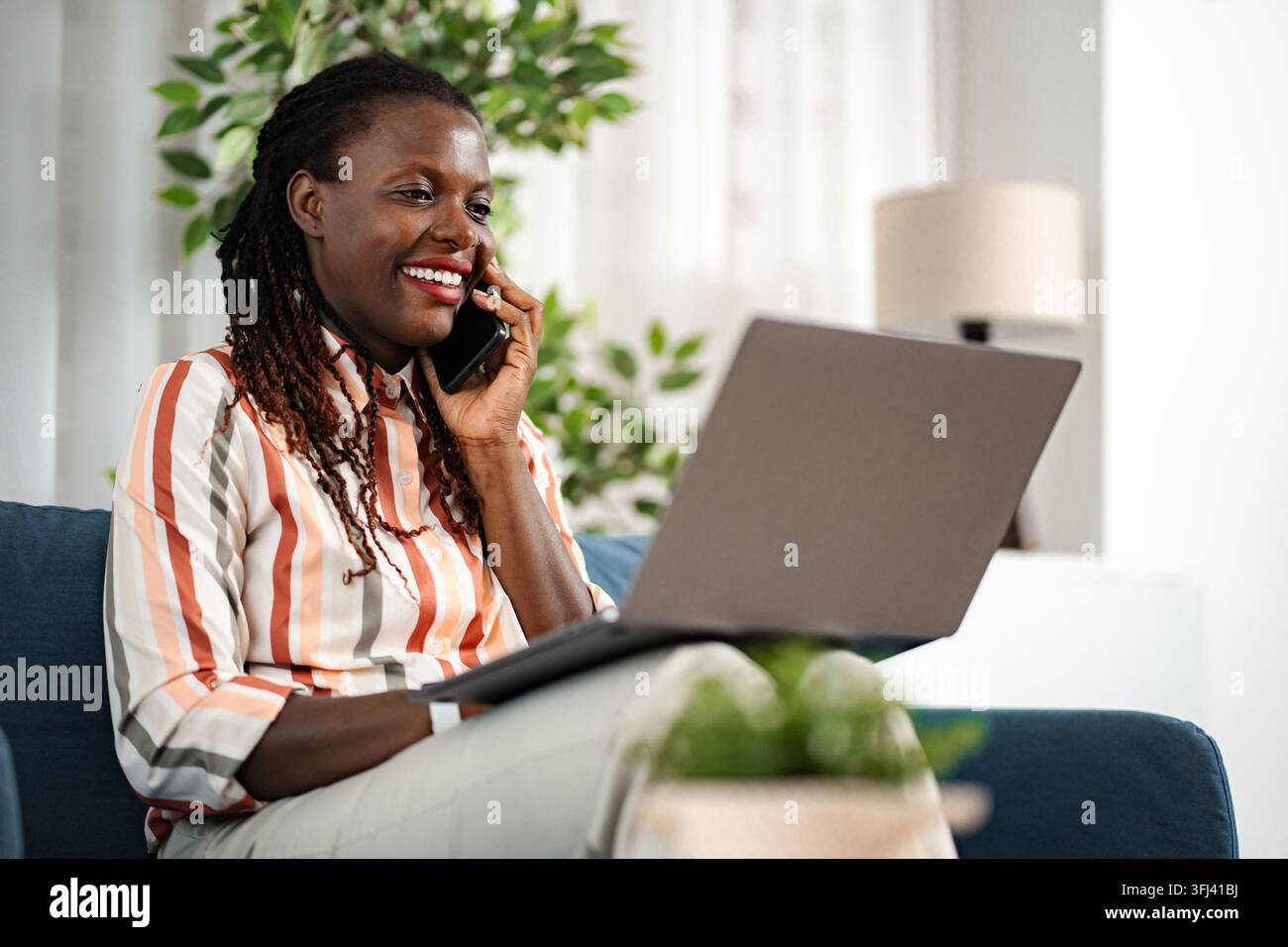 Donna afroamericana che lavora da casa e parla al telefono Foto Stock